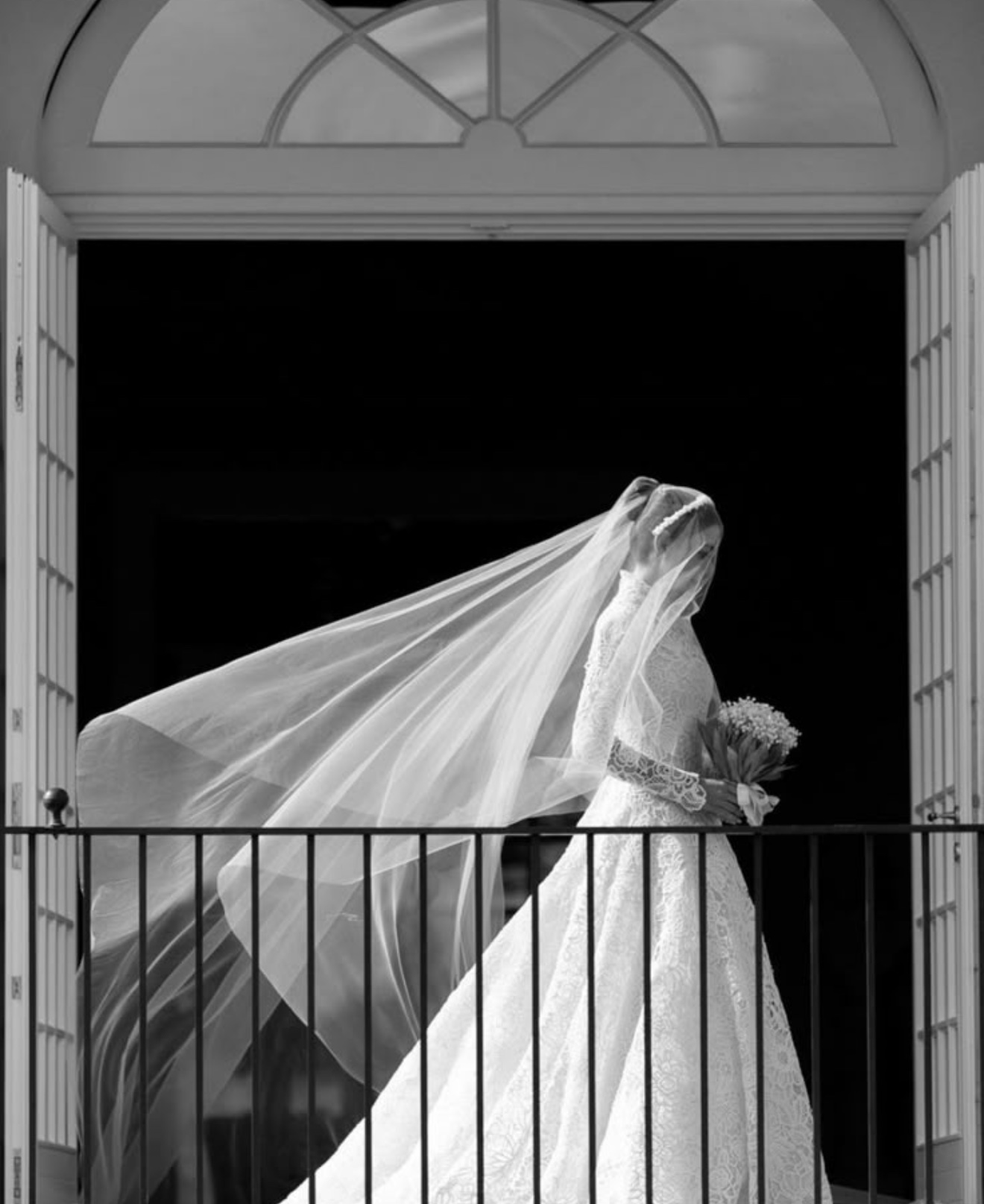 Bride crossing a balcony as her veil moves behind her