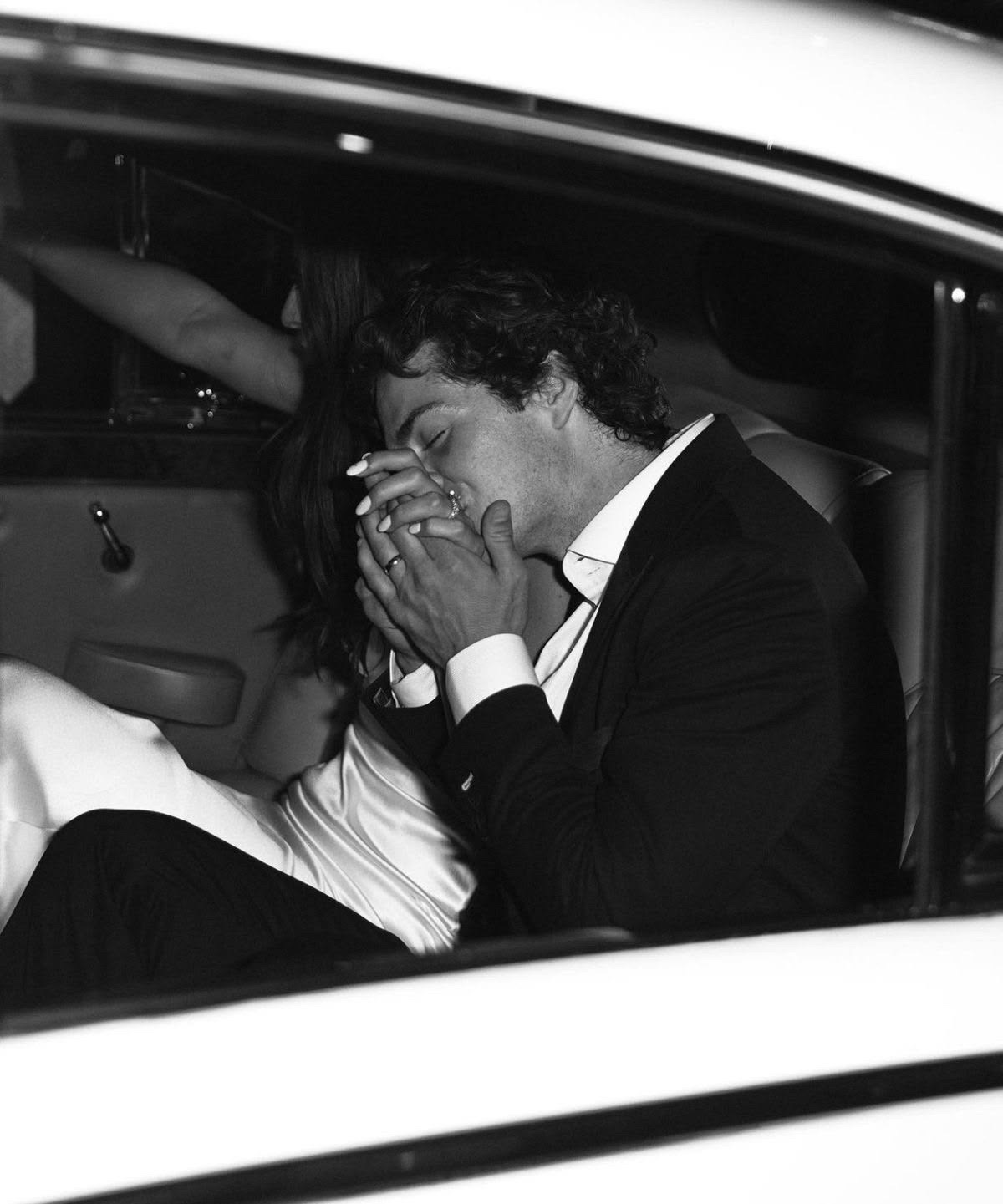 Groom kissing his partner's hand inside a car