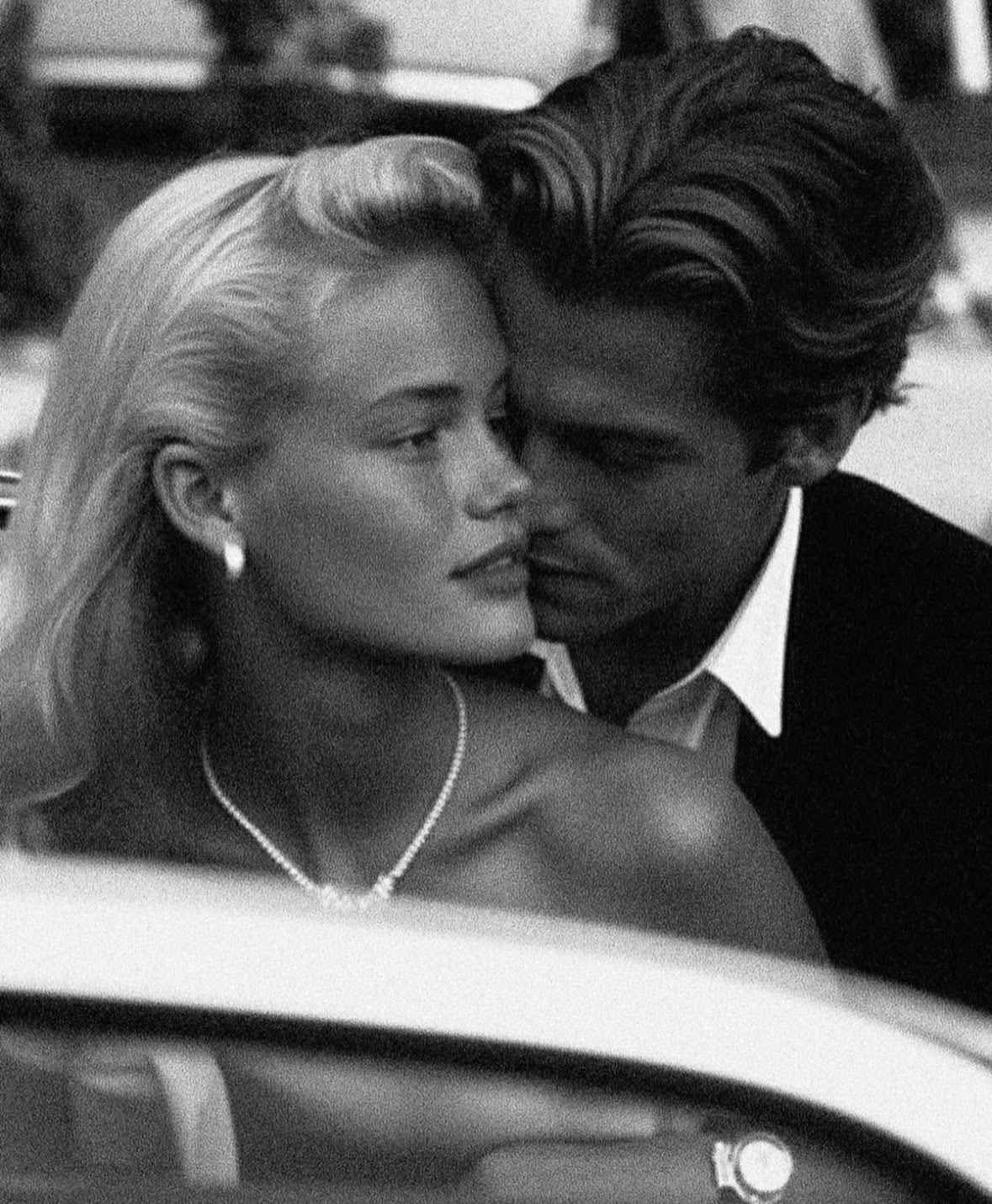 A couple photographed closely inside a vintage car